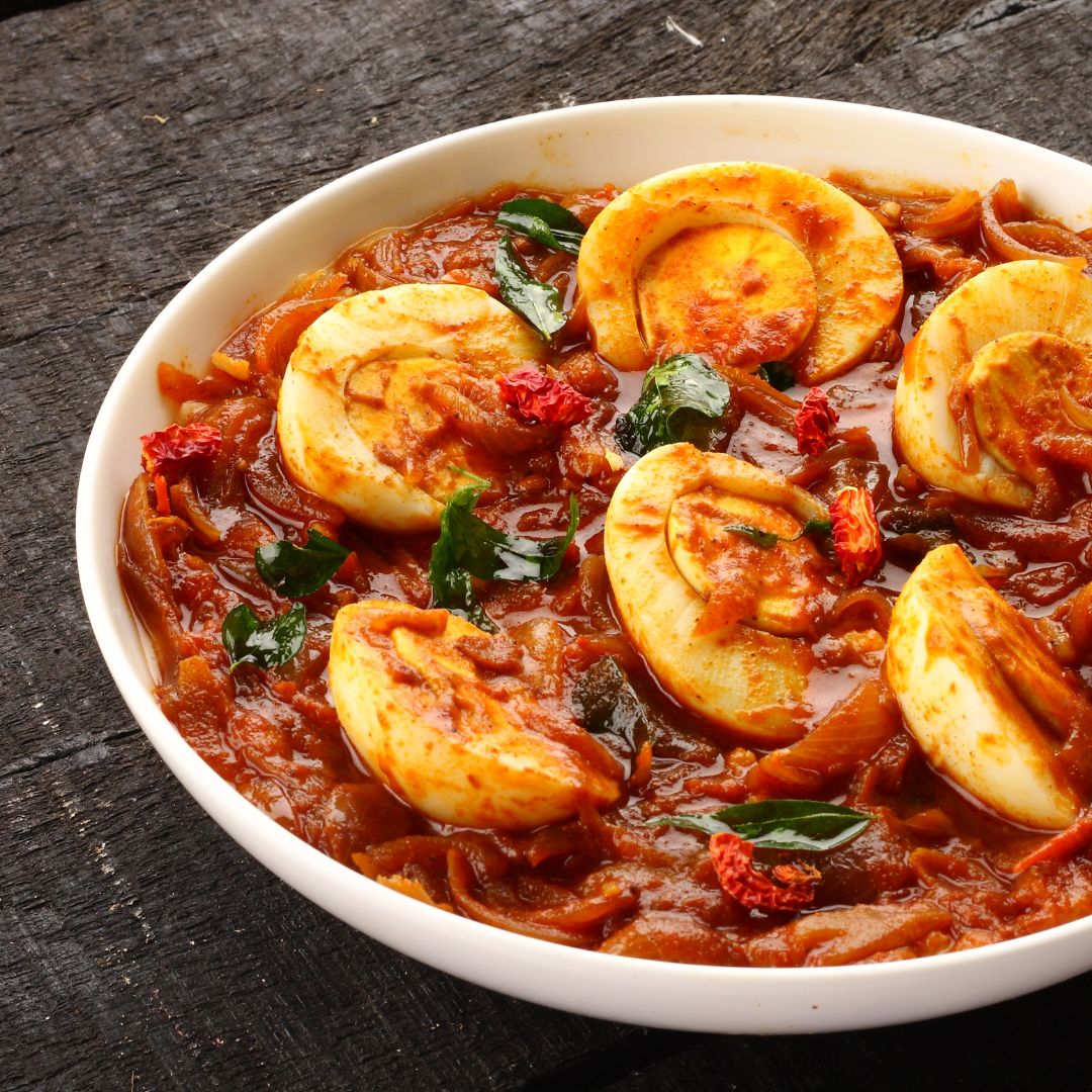 Spicy and flavorful Egg Curry with boiled eggs simmered in a rich tomato and onion gravy, garnished with fresh herbs and dried red chilies.