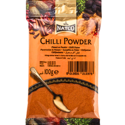 "Natco Chilli Powder 100g package with vibrant orange and gold colors. The package features a spoon and spices such as cinnamon, cloves, and star anise in the background, emphasizing its rich and flavorful use in cooking. The text on the package highlights the product’s details in various languages."